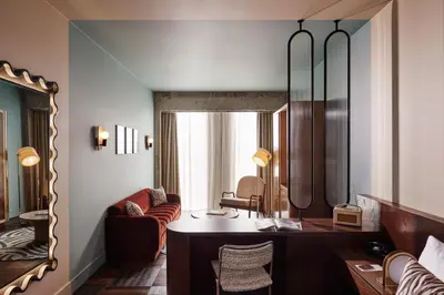 a living room with a desk and a mirror at The Hoxton, Brussels in Brussels