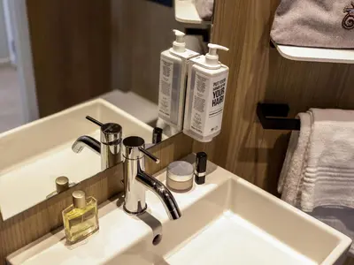 a bathroom sink with two bottles of soap and a mirror at ibis Brussels Groot Bijgaarden in Groot-Bijgaarden