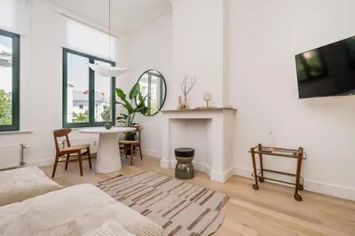 a white living room with a table and a couch at Quartier Le Sud in Antwerp