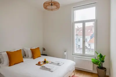 a white bed in a room with a window at Center Royal Residence in Brussels