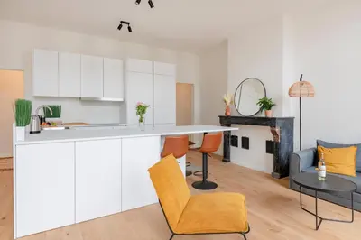 a kitchen and living room with white cabinets and a table at Center Royal Residence in Brussels