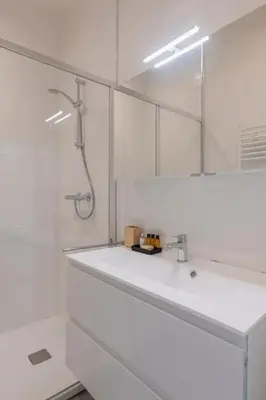 a white bathroom with a sink and a mirror at Center Royal Residence in Brussels