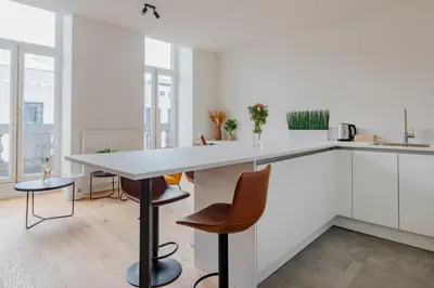 a kitchen with white cabinets and a table and chairs at Center Royal Residence in Brussels