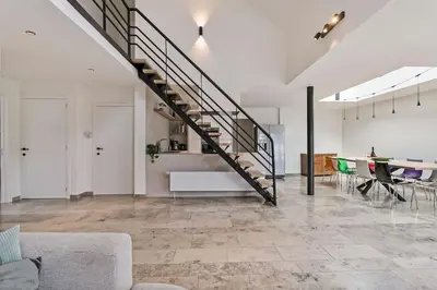 a living room with a staircase and a table with chairs at Schitterende loft met jacuzzi en sauna in Mechelen in Mechelen
