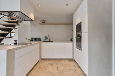 a kitchen with white cabinets and a staircase at Schitterende loft met jacuzzi en sauna in Mechelen in Mechelen