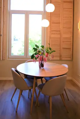 a dining room table with chairs and a vase with flowers at Japandi Apartment, Cityview Elevator in Antwerp