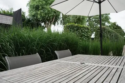 a wooden table with an umbrella and two chairs at The Suite Escape Apartment Sand in Sint-Lievens-Houtem