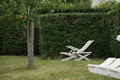 two white chairs sitting in the grass next to an apple tree at The Suite Escape Apartment Sand in Sint-Lievens-Houtem