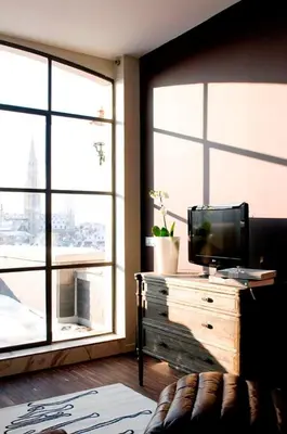 a living room with a tv on a dresser with windows at Apartment Nyhuset in Brussels