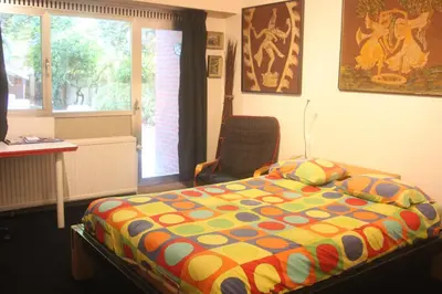 a bedroom with a bed and a chair and a window at B&B Middelheim in Antwerp