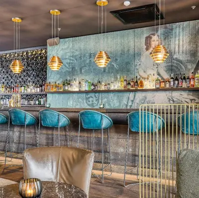 a bar with blue chairs and a wall with a mural at Motel One Brussels in Brussels