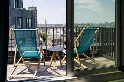 two chairs on a balcony with a view of a city at Motel One Brussels in Brussels