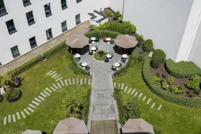 an overhead view of a garden with umbrellas and a building at Motel One Brussels in Brussels