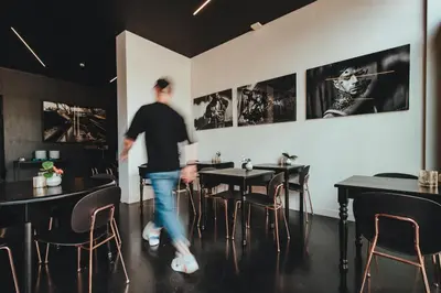 a man walking in a restaurant with tables and chairs at Hotel Elisabeth in Mechelen
