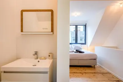a bedroom with a bed and a sink and a mirror at Stylishly furnished private home in a vibrant area in Antwerp