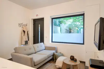 a living room with a couch and a window at Stylishly furnished private home in a vibrant area in Antwerp