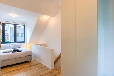 a white bedroom with a bed and a window at Stylishly furnished private home in a vibrant area in Antwerp