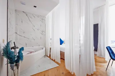 a white bathroom with a tub and a bed at Hotel Les Ecrins in Brussels