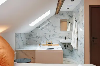 a bathroom with a sink and a marble wall at Hotel Les Ecrins in Brussels