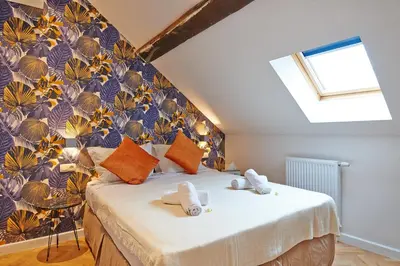 a bedroom with a large bed with a floral wall at Hotel Les Ecrins in Brussels