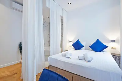 a bedroom with a large white bed with blue pillows at Hotel Les Ecrins in Brussels