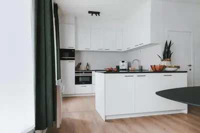a white kitchen with white cabinets and a table at Apartment The City in Ghent