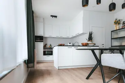 a kitchen with white cabinets and a table at Apartment The City in Ghent