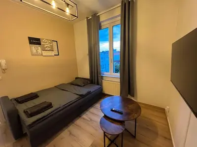 a bedroom with a bed and a table and a window at Cosy Apartment Merode in Brussels