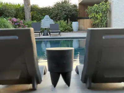 a pool with chairs and a statue in the background at Ikigai B&B - wellness in Oud-Turnhout