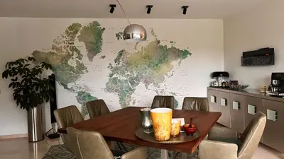 a dining room table with a world map on the wall at Ikigai B&B - wellness in Oud-Turnhout