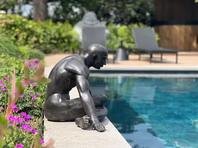 a statue of a woman sitting next to a swimming pool at Ikigai B&B - wellness in Oud-Turnhout