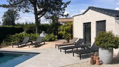 a group of lounge chairs next to a swimming pool at Ikigai B&B - wellness in Oud-Turnhout