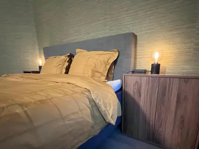 a bedroom with a bed with two lamps on a night stand at Ikigai B&B - wellness in Oud-Turnhout