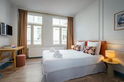 a bedroom with a large white bed and two windows at SHWAY - The Saffron Dress in Antwerp