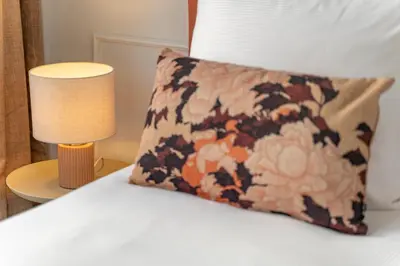 a pillow sitting on a bed next to a lamp at SHWAY - The Saffron Dress in Antwerp