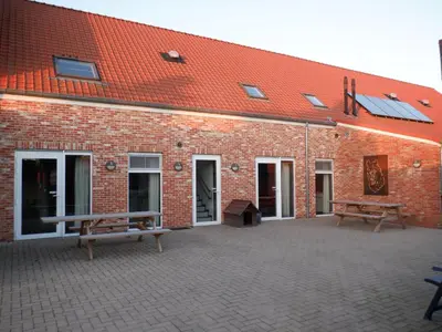 a brick building with two benches in front of it at Hoeve Megusta in Vlimmeren