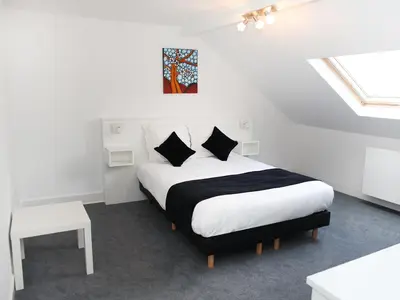 a bedroom with a bed with white sheets and black pillows at Hotel Satellite in Brussels
