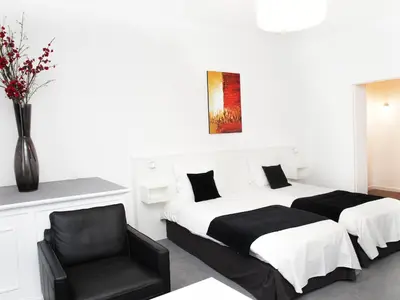 a bedroom with two beds and a black chair at Hotel Satellite in Brussels