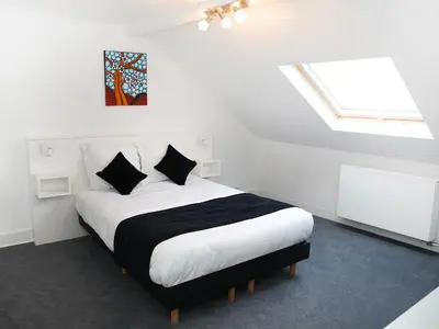 a white bedroom with a bed with black pillows at Hotel Satellite in Brussels