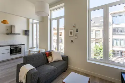 a living room with a couch and some windows at Nice furnished appartement AAA- location in Antwerp