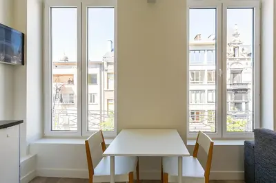a white table and chairs in a room with windows at Nice furnished appartement AAA- location in Antwerp