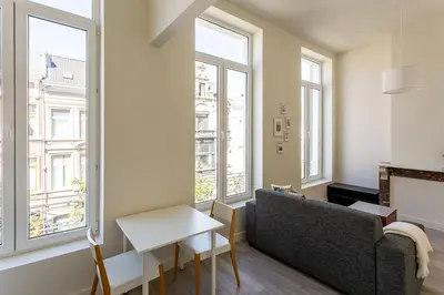 a living room with windows and a couch and a table at Nice furnished appartement AAA- location in Antwerp