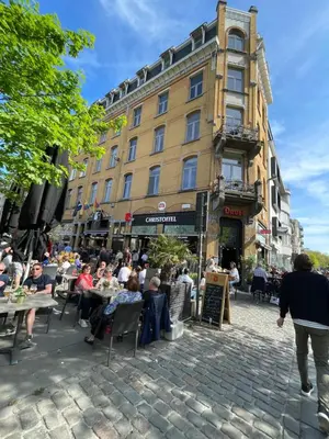 a group of people sitting at tables in front of a building at Modern apartment with terrace at Theaterplein in Antwerp