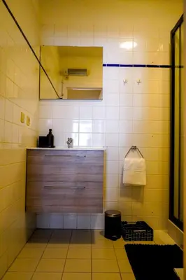 a bathroom with a sink and a shower with yellow tiles at Garden Botanique Apartment in Brussels