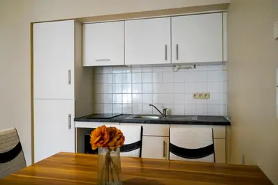 a kitchen with white cabinets and a wooden table at Garden Botanique Apartment in Brussels