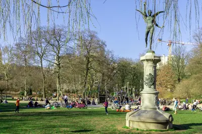 a statue in a park with people sitting on the grass at OneLuxStay near Diamond District in Antwerp