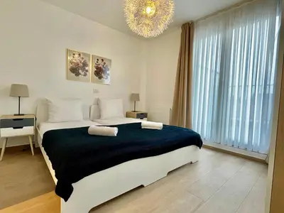a bedroom with a large bed and a chandelier at OneLuxStay near Diamond District in Antwerp