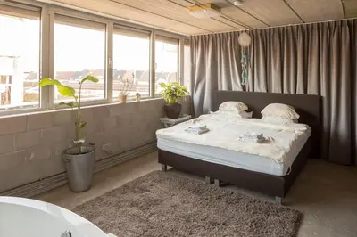 a bedroom with a bed in a room with windows at Mari's: Multifunctional Shelter with big Garden in Ghent