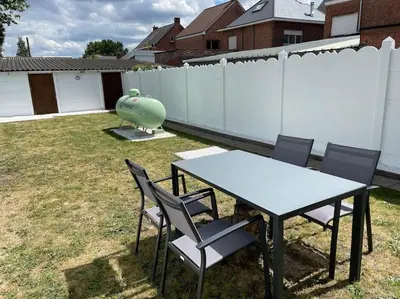 a table and chairs in a backyard with a fence at Cosy flat for 4 p. with garden in Tremelo in Tremelo