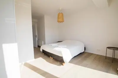 a white bedroom with a bed and a table at TravelEase - Midi in Brussels